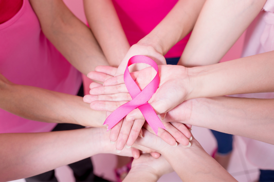 Women who are holding a pink ribbon for breast cancer awareness